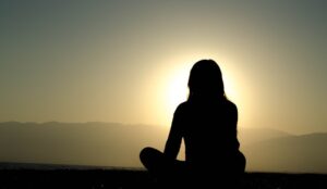 Control your subconscious mind; silhouette of a person sitting and watching the sunset from the top of an elevated place