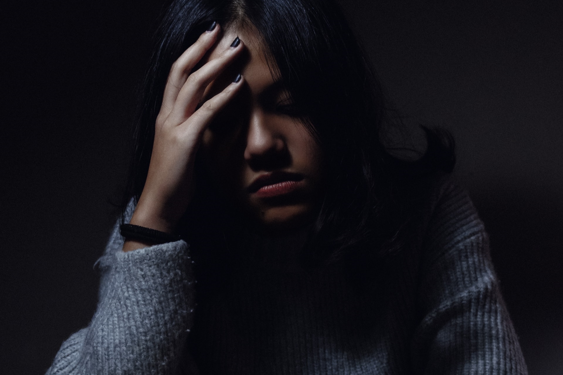 Hypnotherapy for Confidence; a woman sitting on the table with a hand on her head