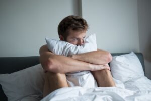 assertive communication, a man holding a pillow in bed