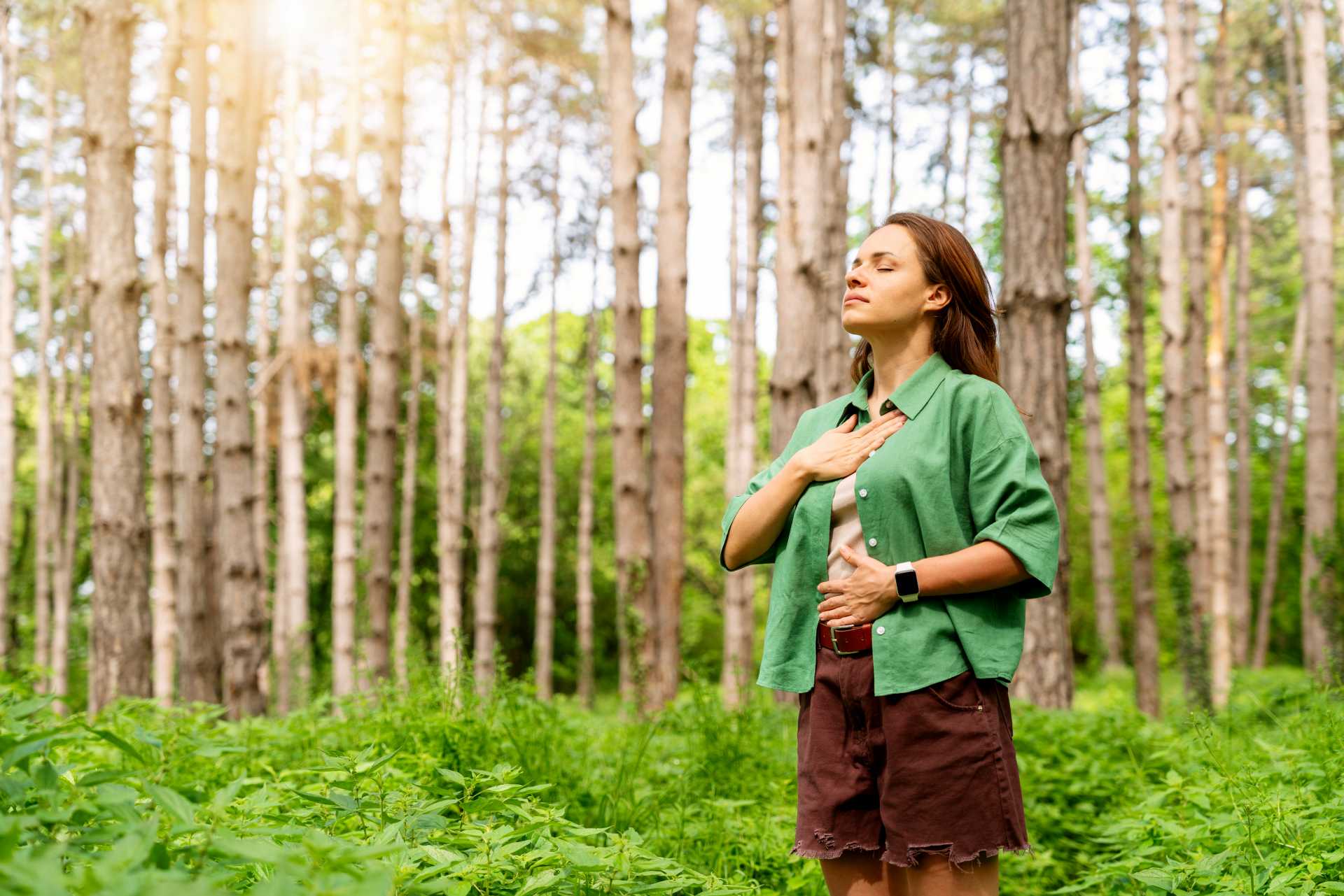 calm your nervous system, A woman practising breathwork in a forest clearing.