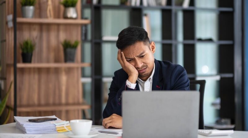career growth strategies, A businessman looks tiredly at a computer monitor and feels hopeless