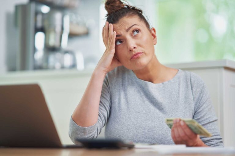 constant worry about finances, A woman holding cash and looking worried.