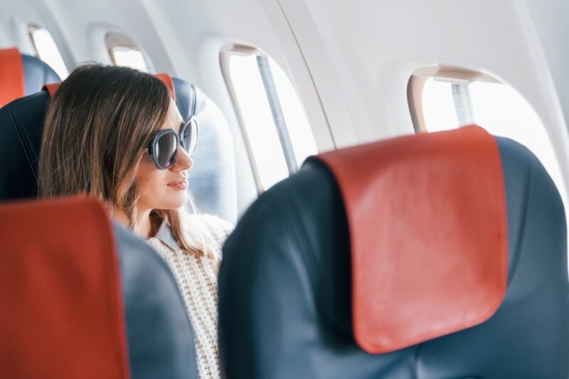 light anxiety tips, a woman confidently looking out of a plane's window