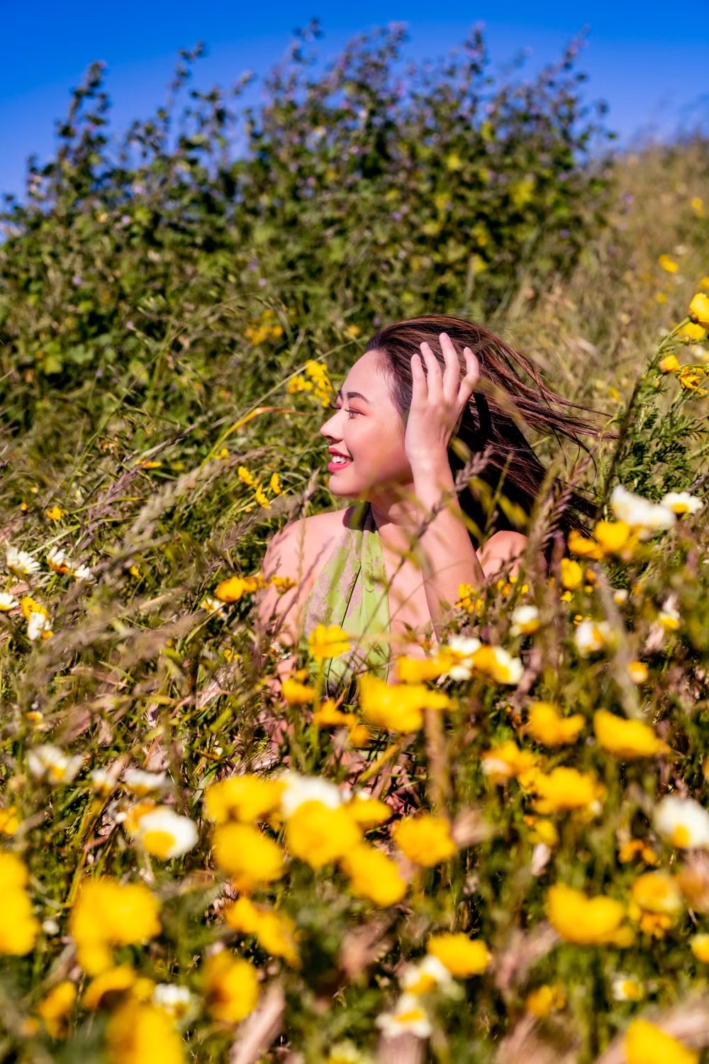 Smiling woman enjoying a sunny meadow filled with yellow wildflowers