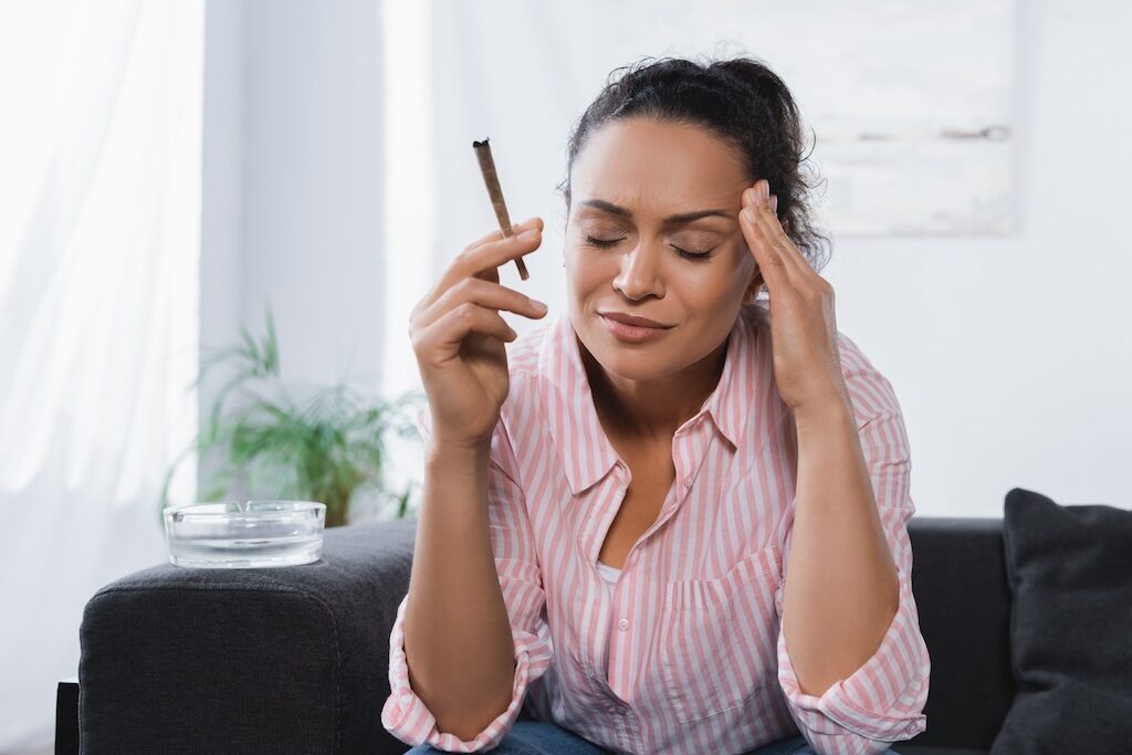impact of cannabis on the brain, woman holding a marijuana cigarette and her head